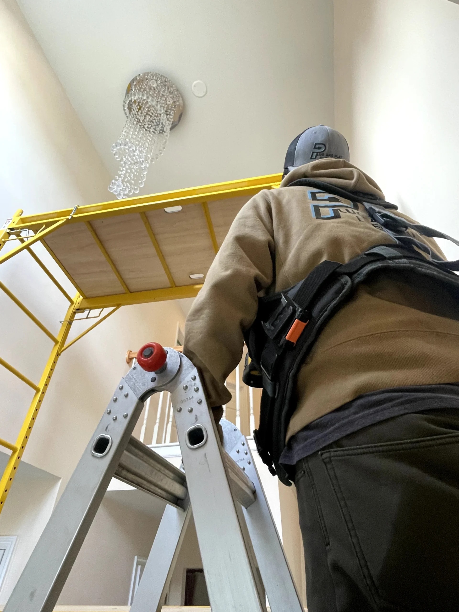 Electrician installing a chandelier in a New Castle, DE home